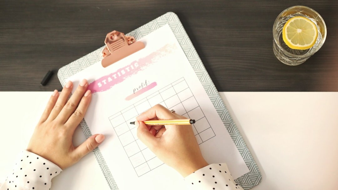 Hands writing household budget figures in a planner next to coins